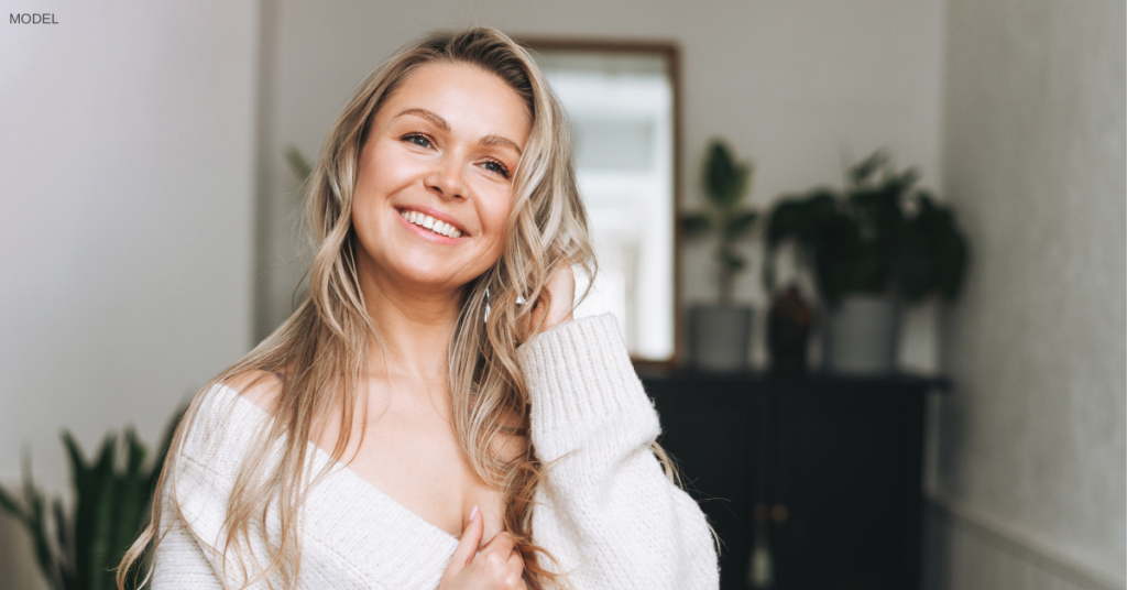 Woman in her 30s (model) smiles while standing indoors